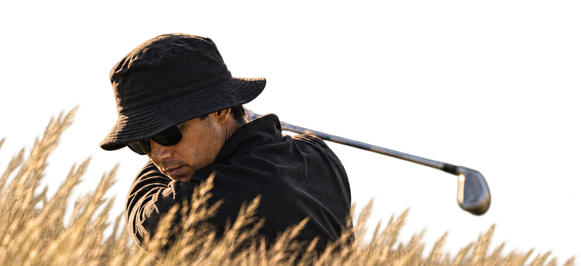 A golfer finishing his swing in the tall grass of a golf course.